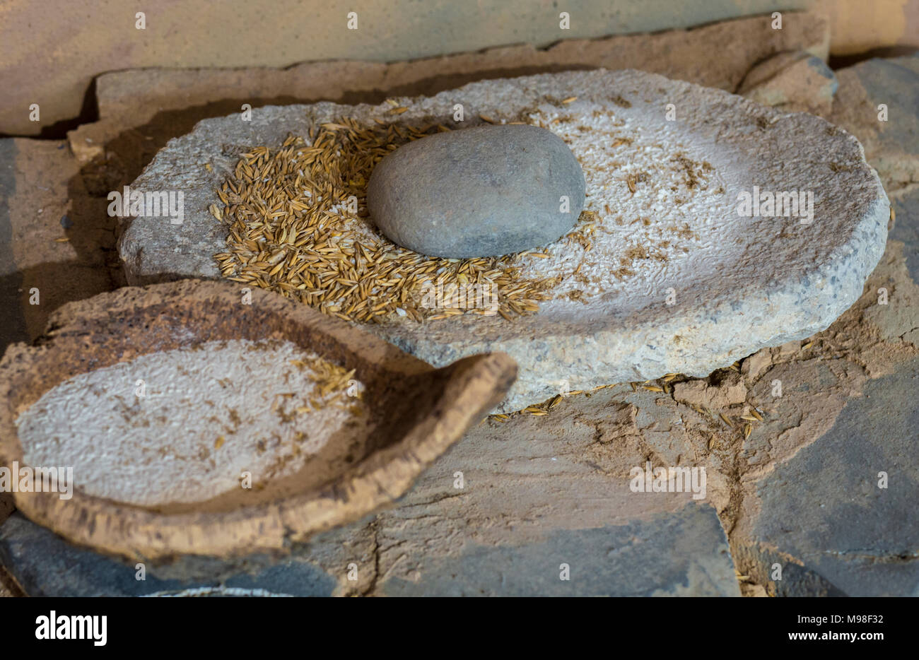 Jaen, Spagna - Dicembre 29th, 2017: neolitico macina di pietra con orzo farina e ciotola in sughero. Messa a fuoco selettiva. Museo di Jaen Foto Stock