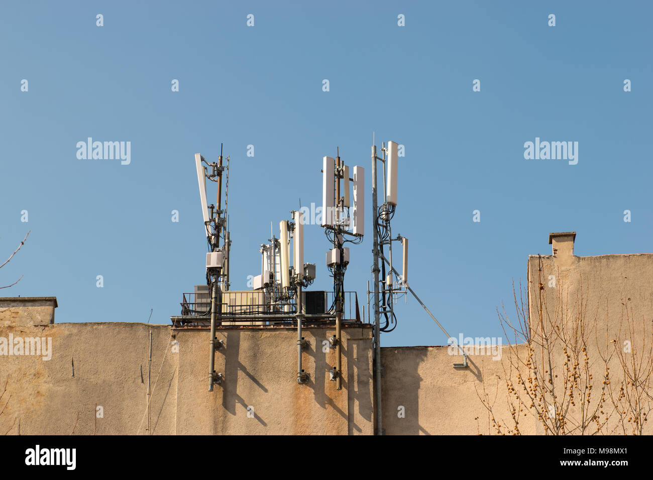 Antenna mobile sul tetto di un edificio contro il cielo blu. Radiodiffusione e comunicatori di rete, ricevitori. Telefono moderno e tecnologia di comunicazione Foto Stock