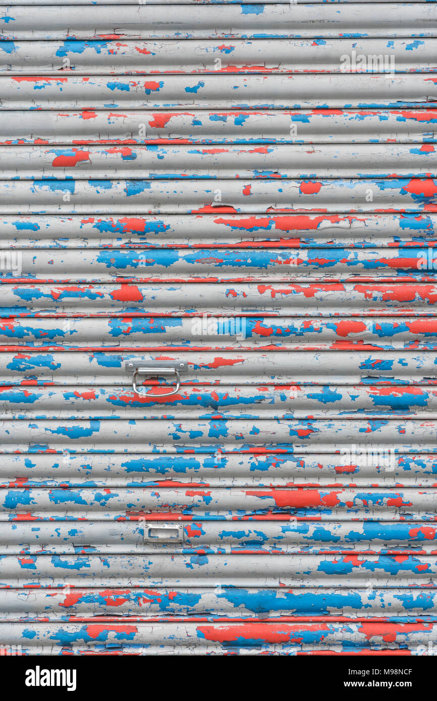 Martoriato di rullo di chiusura sportello con peeling vernice. Metafora chiusa per business, high street crisi, vacante negozi. La vecchia vernice texture, ostruita. Foto Stock