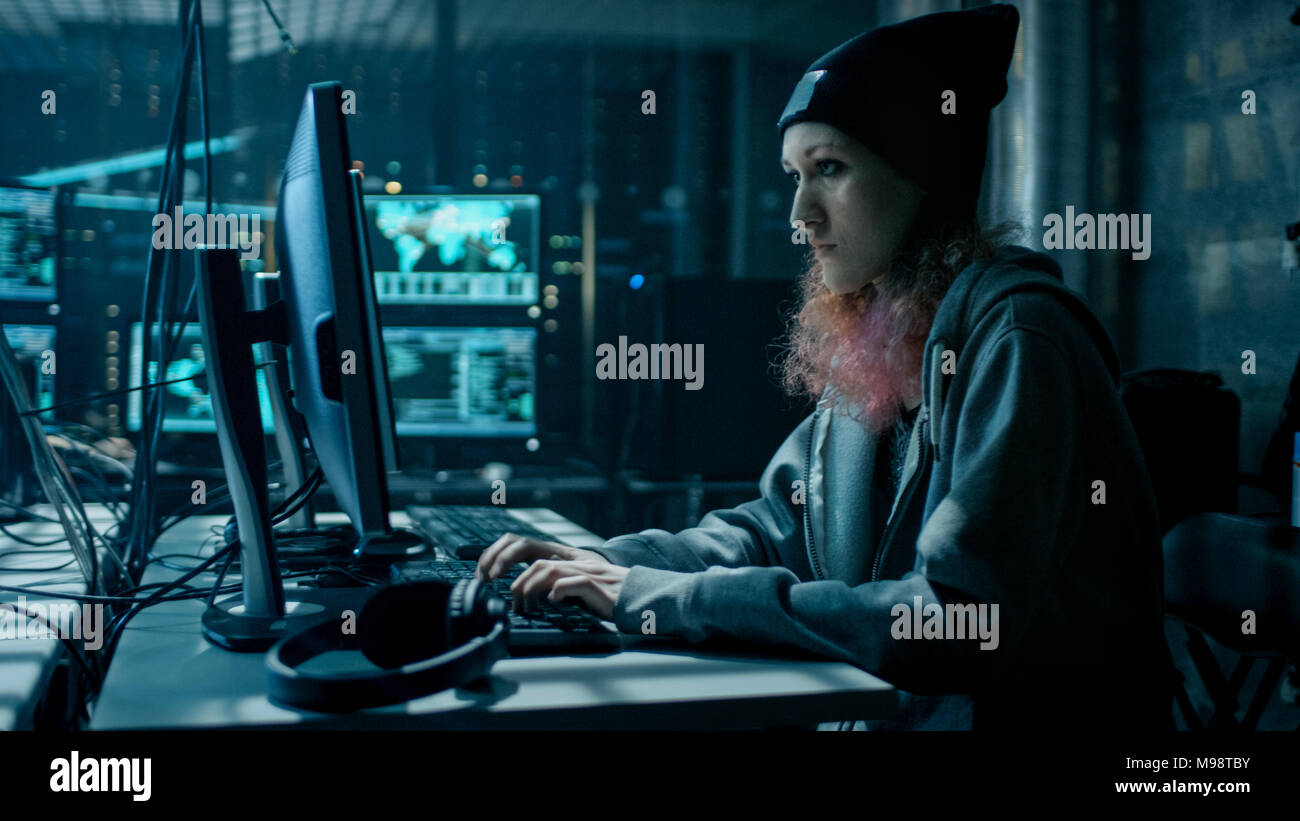 Anticonformista hacker adolescenti ragazza utilizzando il computer per attaccare i server aziendali con malware. La camera è scuro, Neon e ha molti Visualizza. Foto Stock