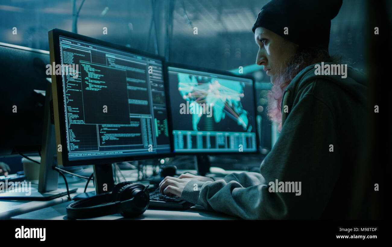 Anticonformista adolescente ragazza Hacker utilizza il suo computer per organizzare attacchi di malware su scala globale. Lei è in metropolitana località segreta piena di Monitor. Foto Stock