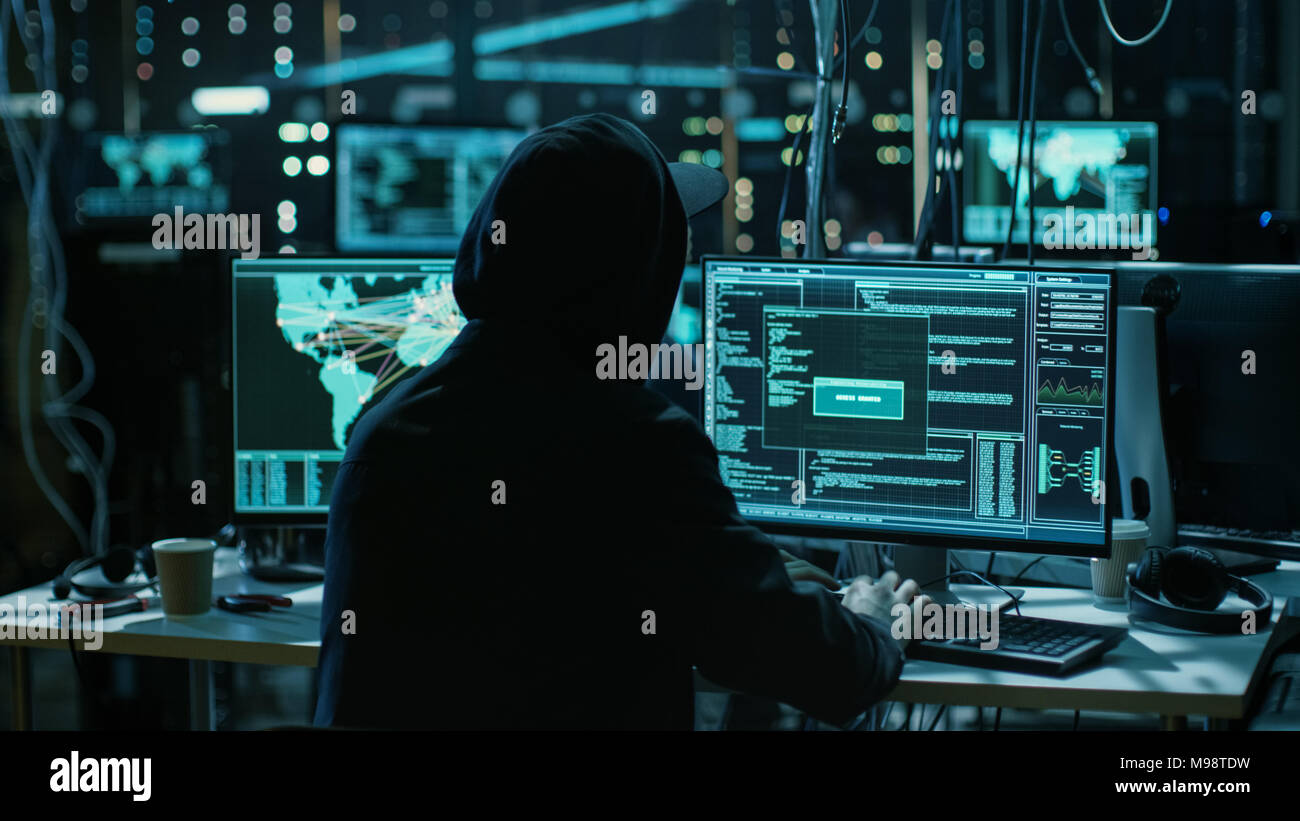 Hacker adolescenti che lavora con il suo computer di infettare i server e infrastruttura con malware. Il suo nascondiglio è scuro, illuminati al neon e ha più display. Foto Stock