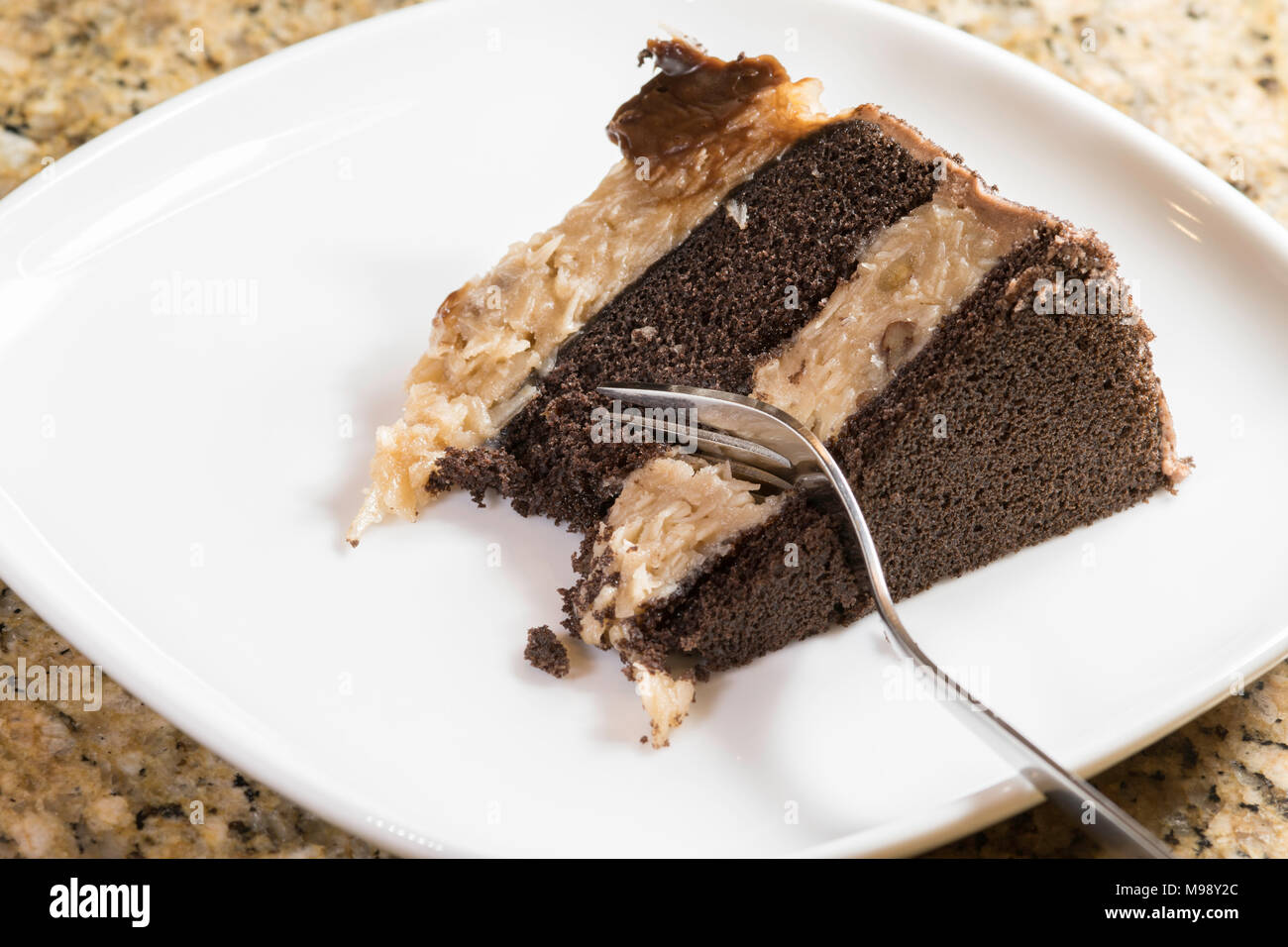 Pezzo di tedesco torta al cioccolato su una piastra bianca con una forcella taglio in essa Foto Stock