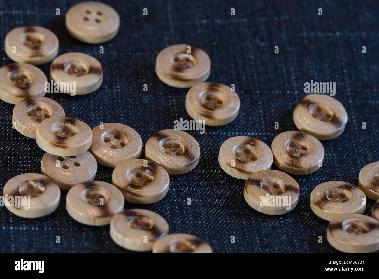 Pulsanti di legno per cucire su un tessuto denim sfondo Foto Stock