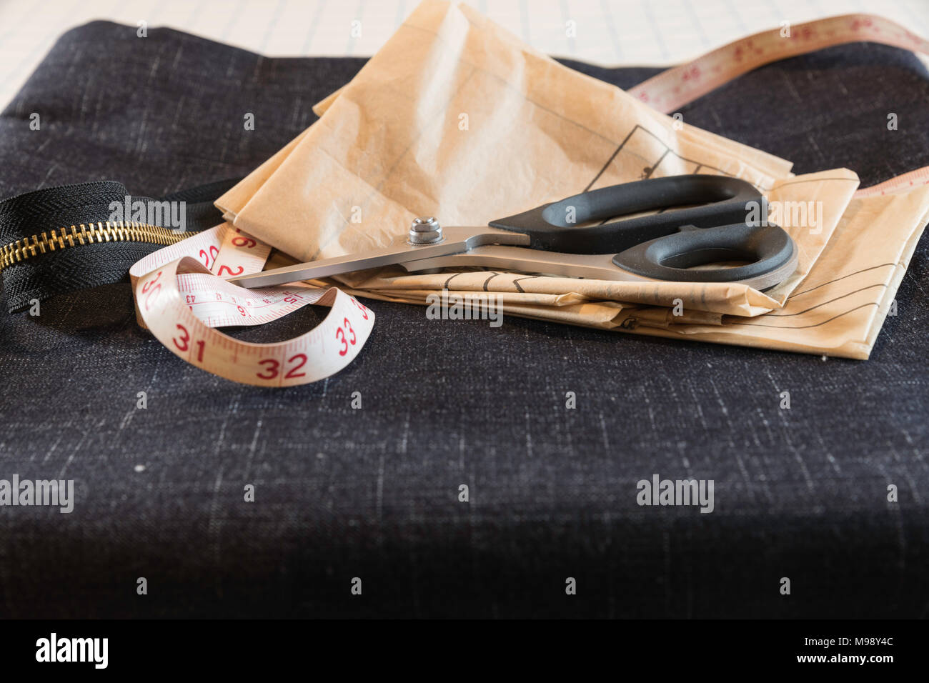 Tutti i materiali di consumo si sono riuniti per iniziare la cucitura con il denim comprese le forbici, nastro di misurazione e di moda tessuto modello Foto Stock