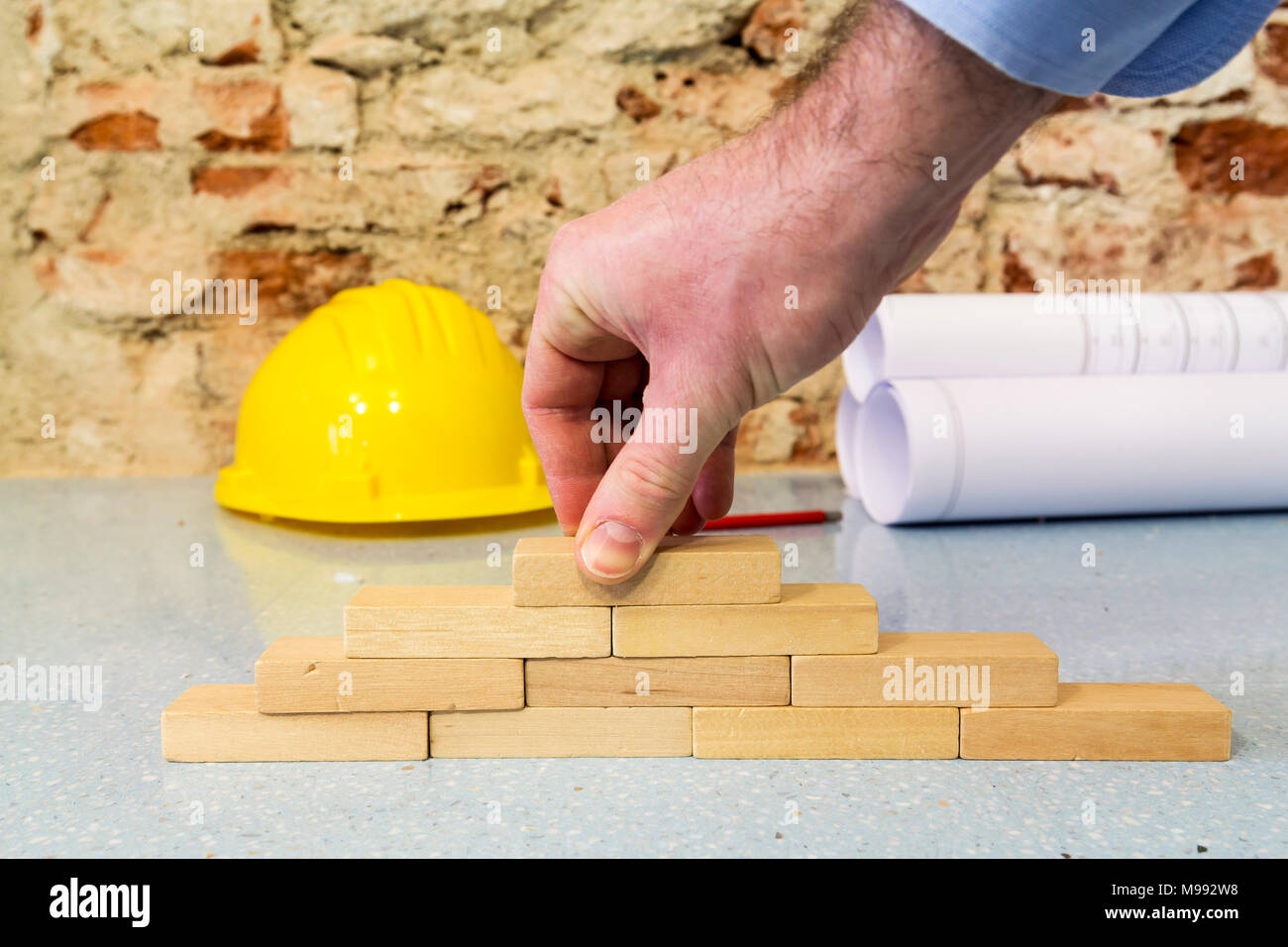 Impresa di costruzioni: la mano la costruzione di una parete in piccoli blocchi di legno Foto Stock