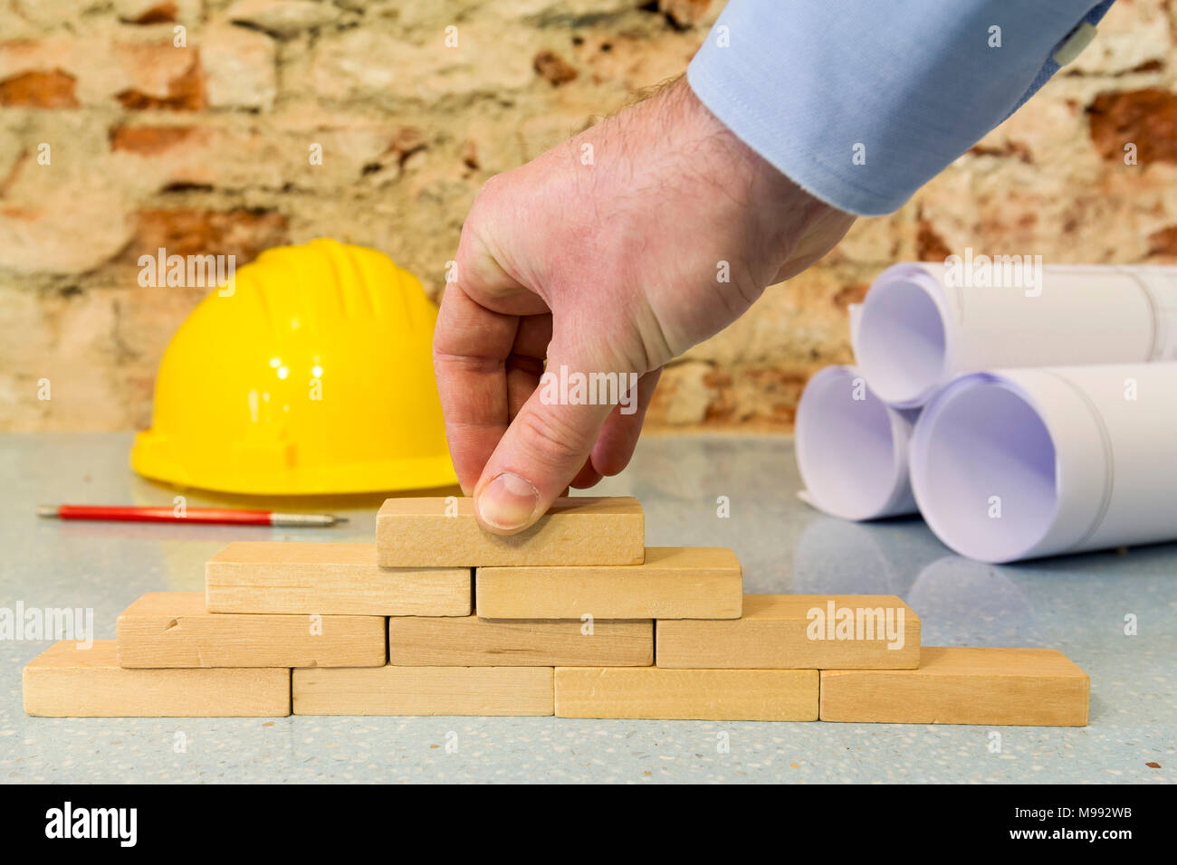 Impresa di costruzioni: la mano la costruzione di una parete in piccoli blocchi di legno Foto Stock