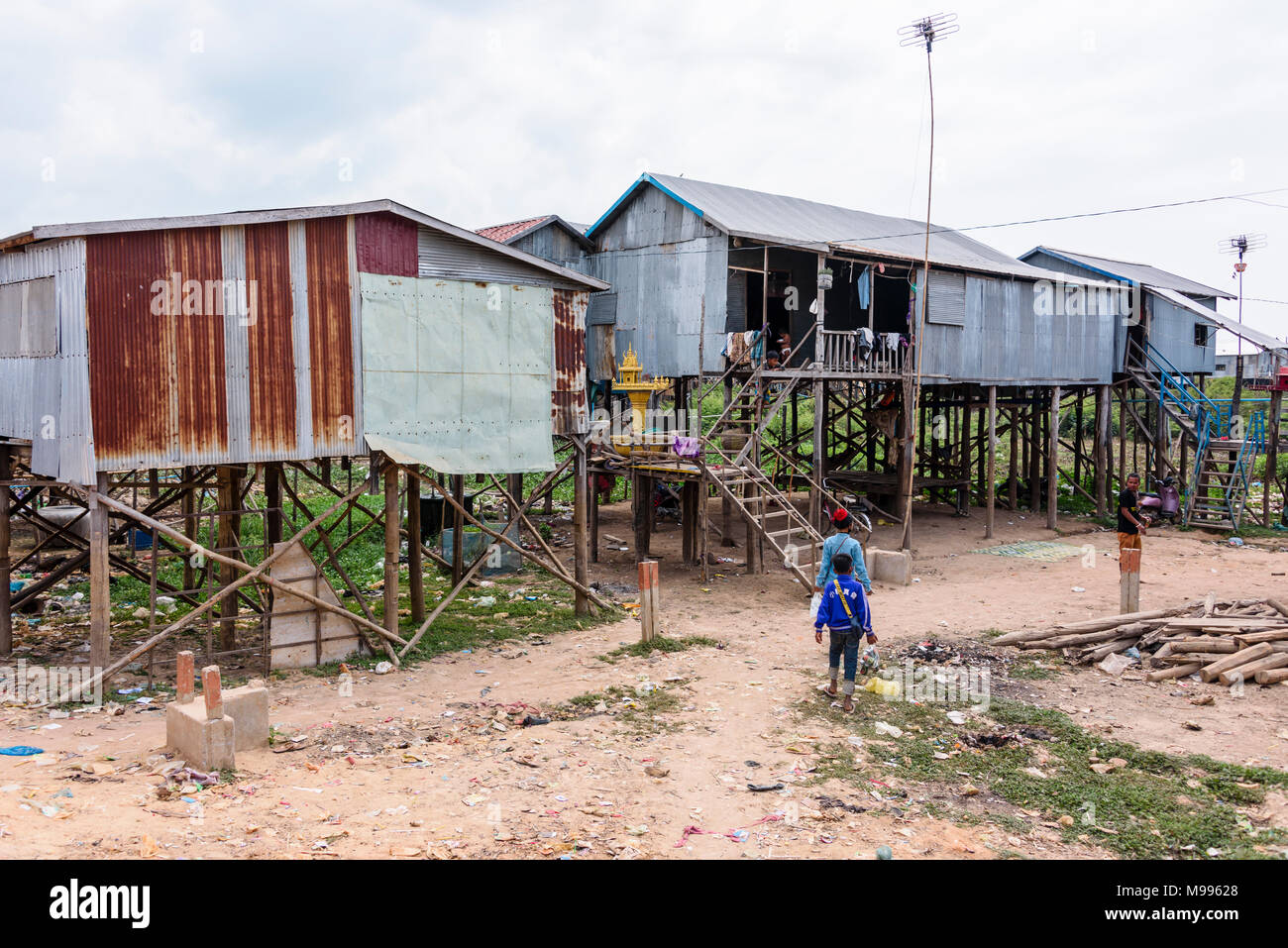 Case fatte dal ferro corrugato su palafitte di legno in un povero villaggio rurale con una pista sterrata strada in Cambogia. Foto Stock