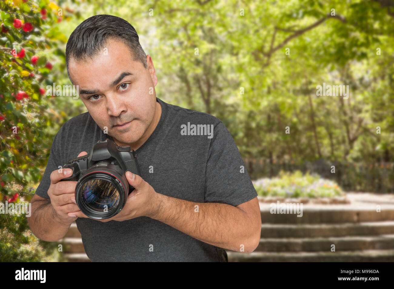Ispanico maschio giovane fotografo con fotocamera DSLR all'aperto Foto Stock