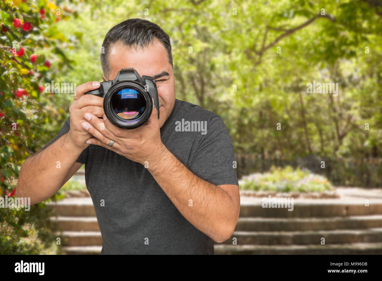 Ispanico maschio giovane fotografo con fotocamera DSLR all'aperto Foto Stock