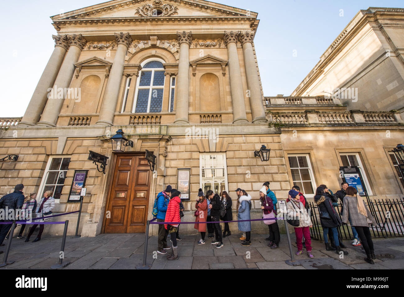 Un gruppo di turisti cinesi coda fuori l'ingresso al centro storico camere della pompa nella vasca da bagno in una giornata di sole in inverno in attesa per le porte da aprire Foto Stock