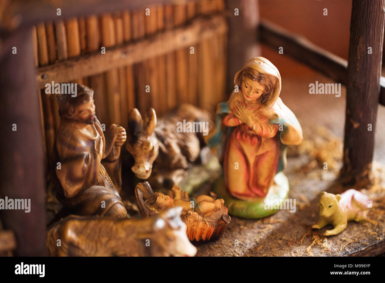 Un antico porcellana dipinta scena della Natività (creche) con Maria e Giuseppe e il Bambino Gesù nel presepe, all'interno di una stalla in legno. Foto Stock