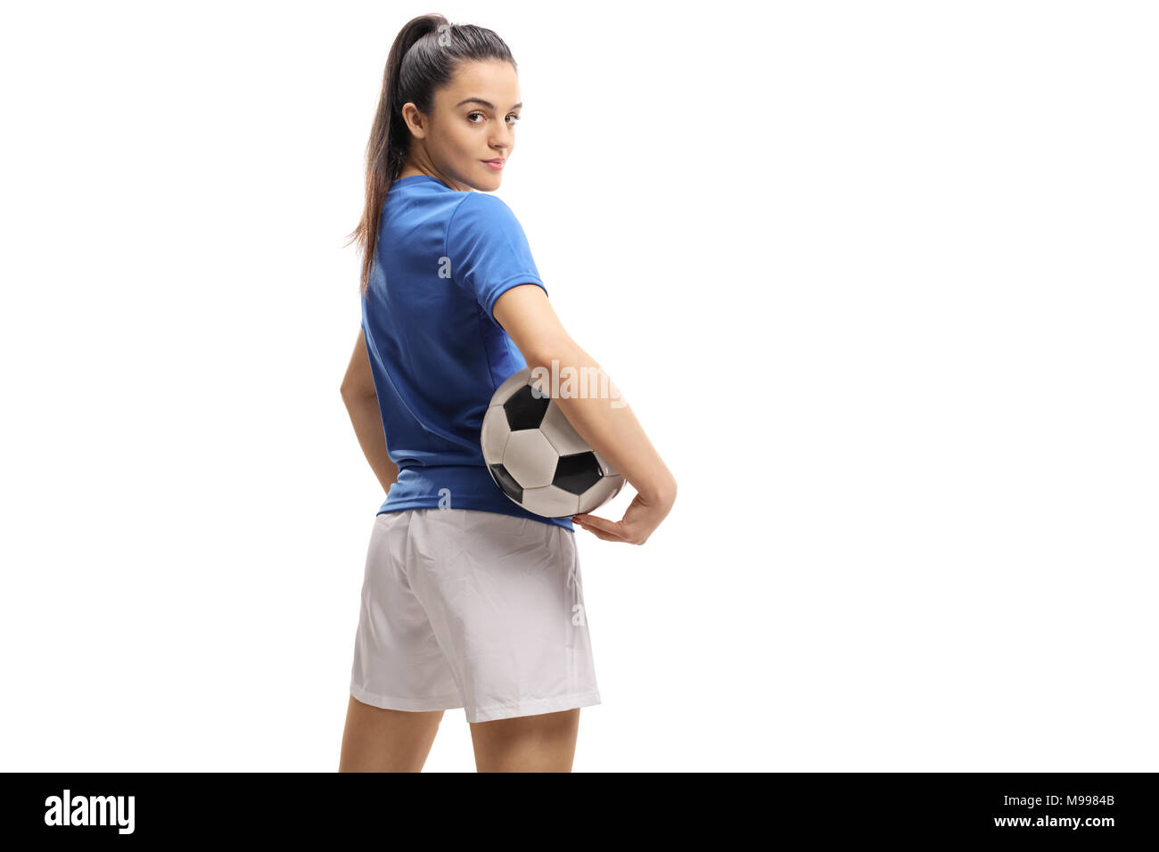 Femmina giocatore di calcio con un pallone da calcio guardando sopra la sua spalla isolati su sfondo bianco Foto Stock