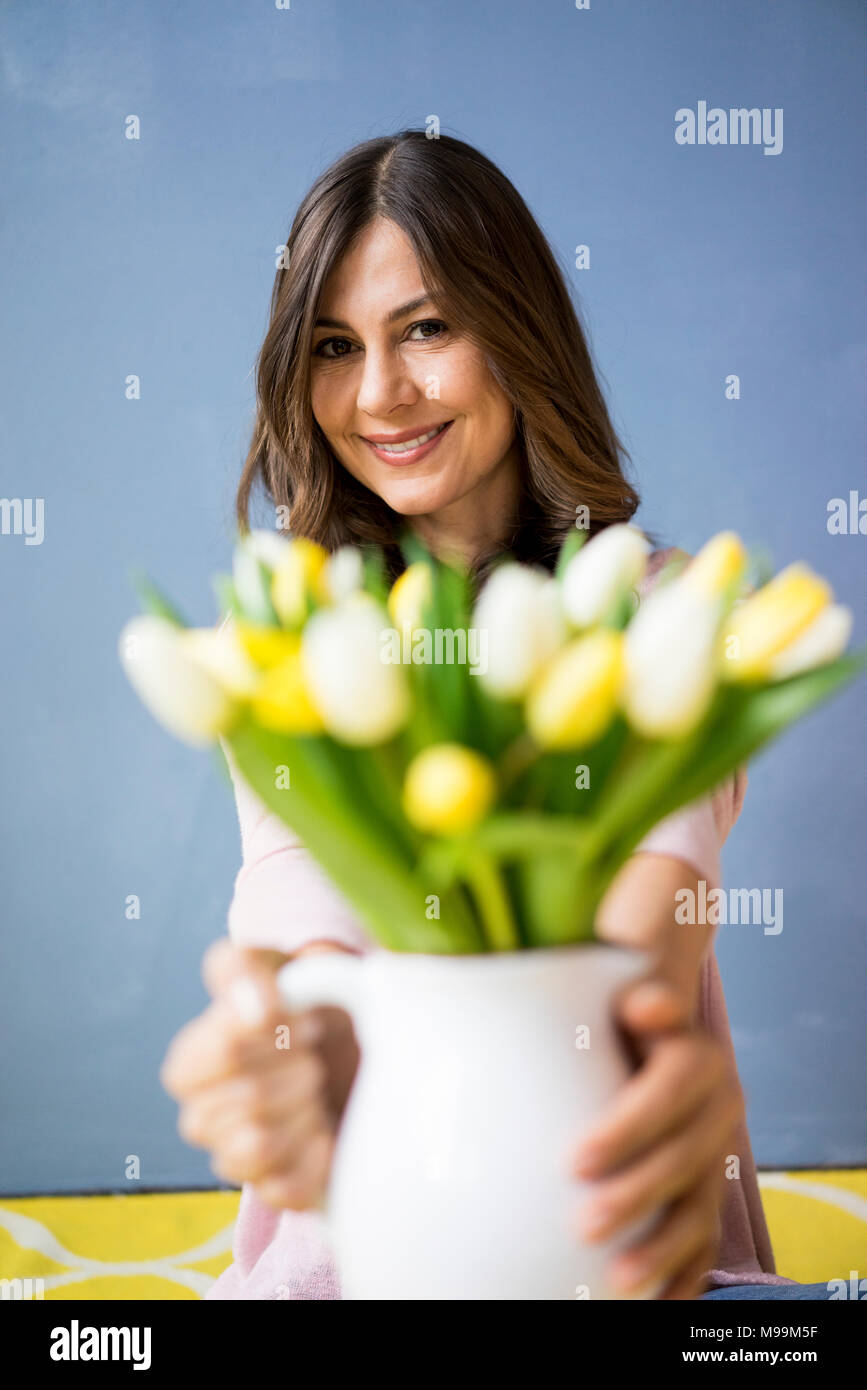 Ritratto di donna sorridente holding mazzo di tulipani in un vaso Foto Stock