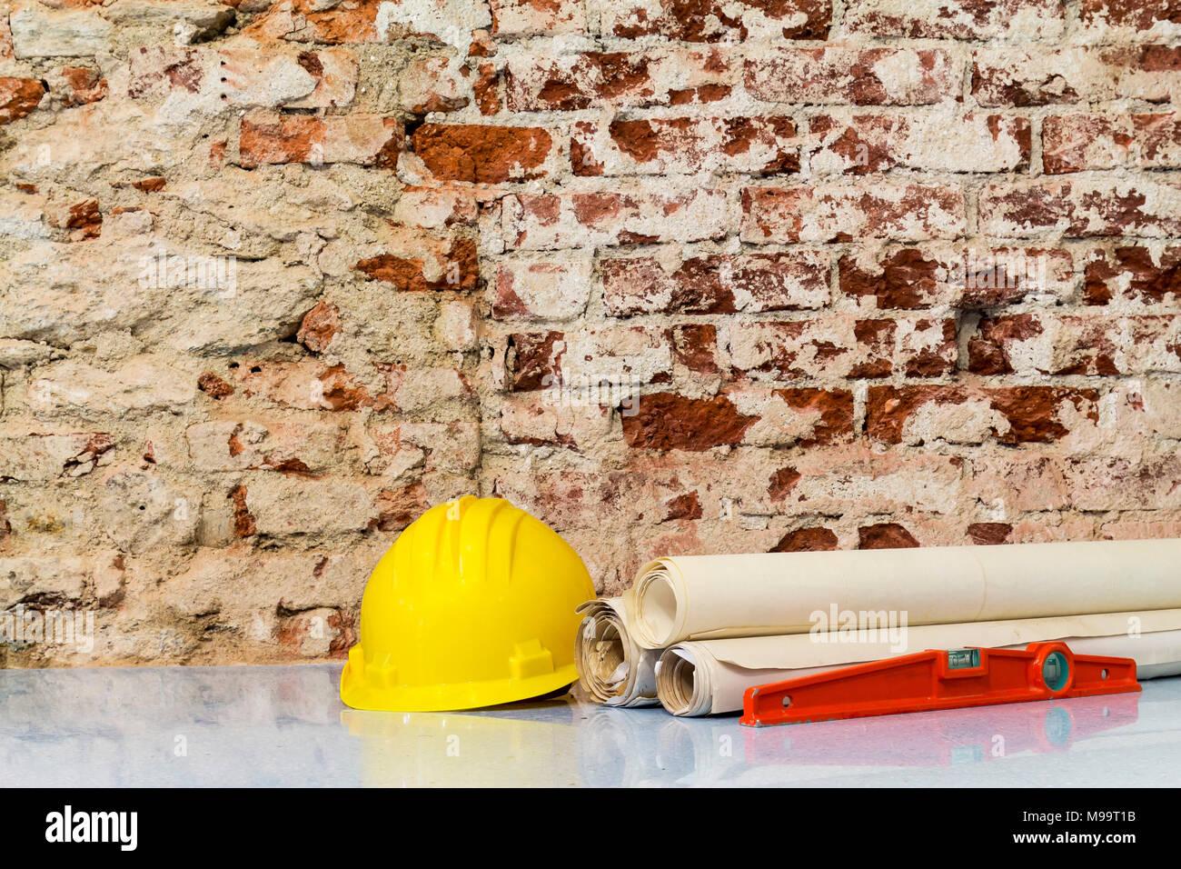 Costruzione di edifici: casco di sicurezza e disegni di progetto su un muro di mattoni sfondo Foto Stock