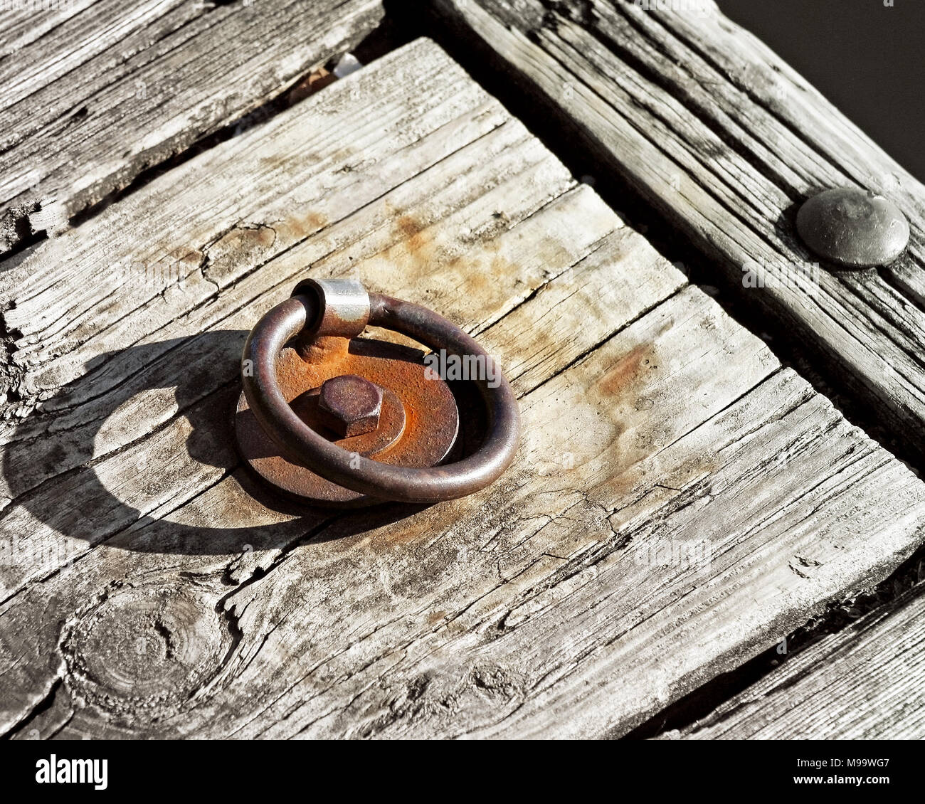 Il vecchio metallo arrugginito dock anello attaccato al molo in legno Foto Stock