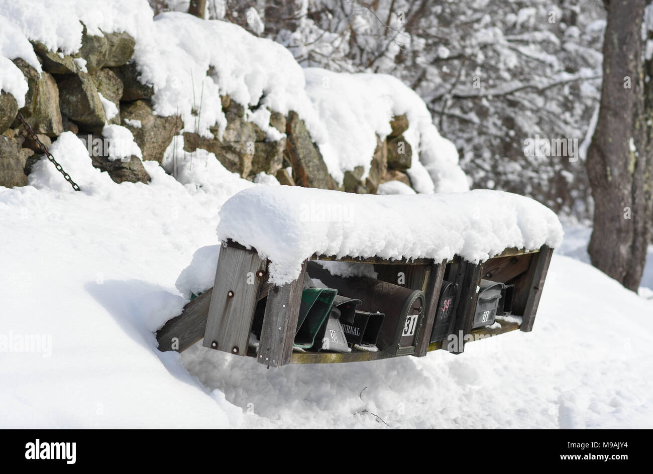 Una fila di caselle di posta e un muro di pietra ricoperta di neve dopo una tempesta di neve Foto Stock