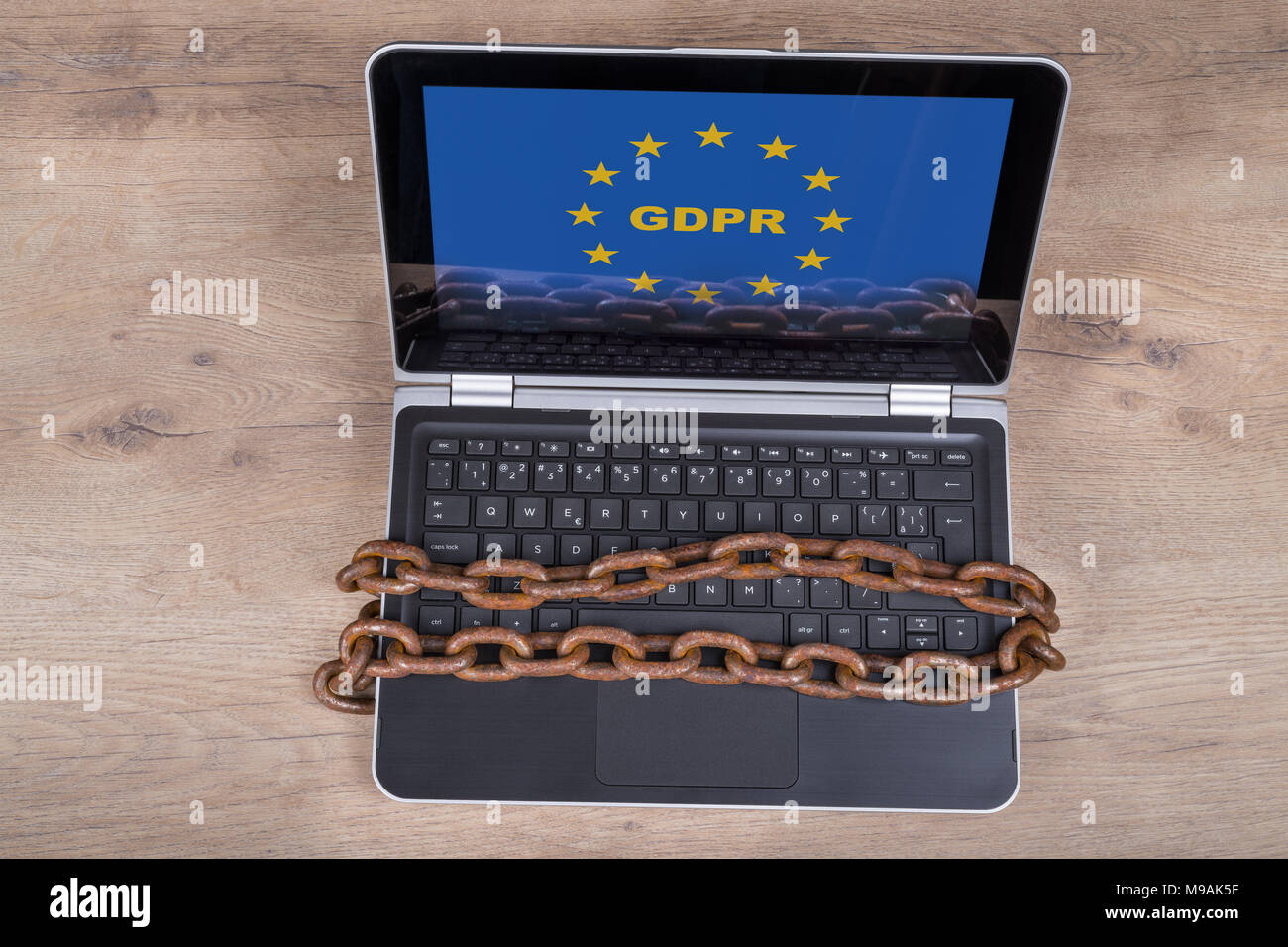 Computer portatile con il PILR lettere in ue stelle su uno sfondo di legno. Tastiera bloccata dal vecchio arrugginito catene. Protezione dei dati personali, la digitalizzazione e la burocrazia. Foto Stock