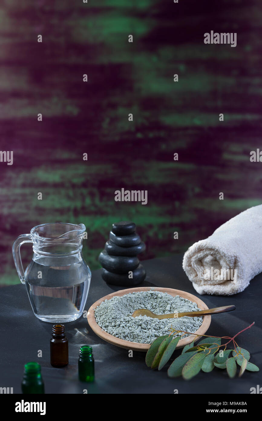 Beaty e spa concept: mortaio di vetro con foglia di eucaliptus, essenziale oin, asciugamano bianco cupp di argilla su pennellate con spessore della vernice in sfumature di verde, blu, viola texture di legno Foto Stock