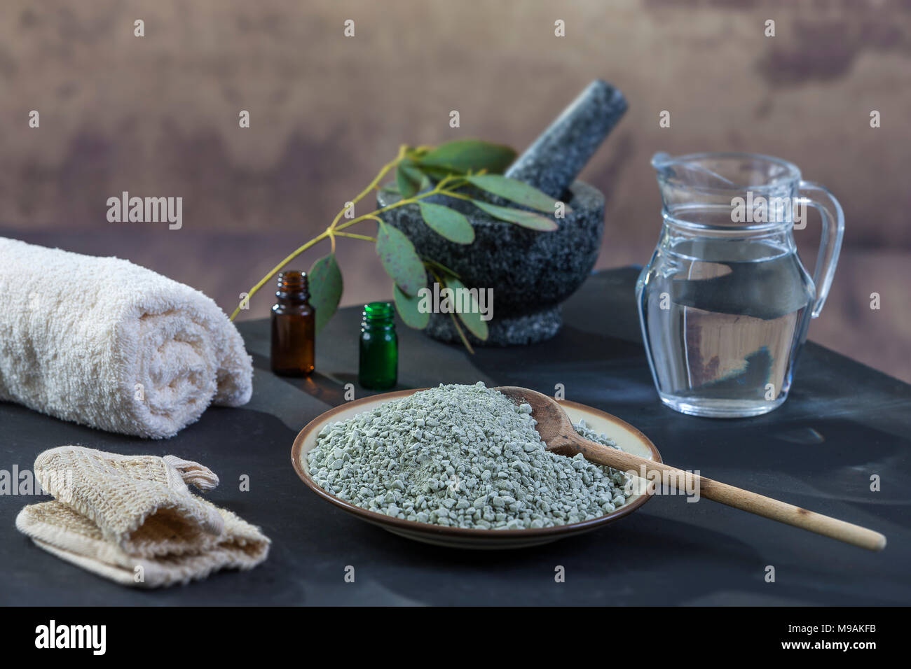 Spa la composizione su legno nero. Sfondo bianco asciugamani laminati, esfoliazione guanto, pioggia guanto, eucalipto , verde, argilla Maschera per viso e corpo Foto Stock