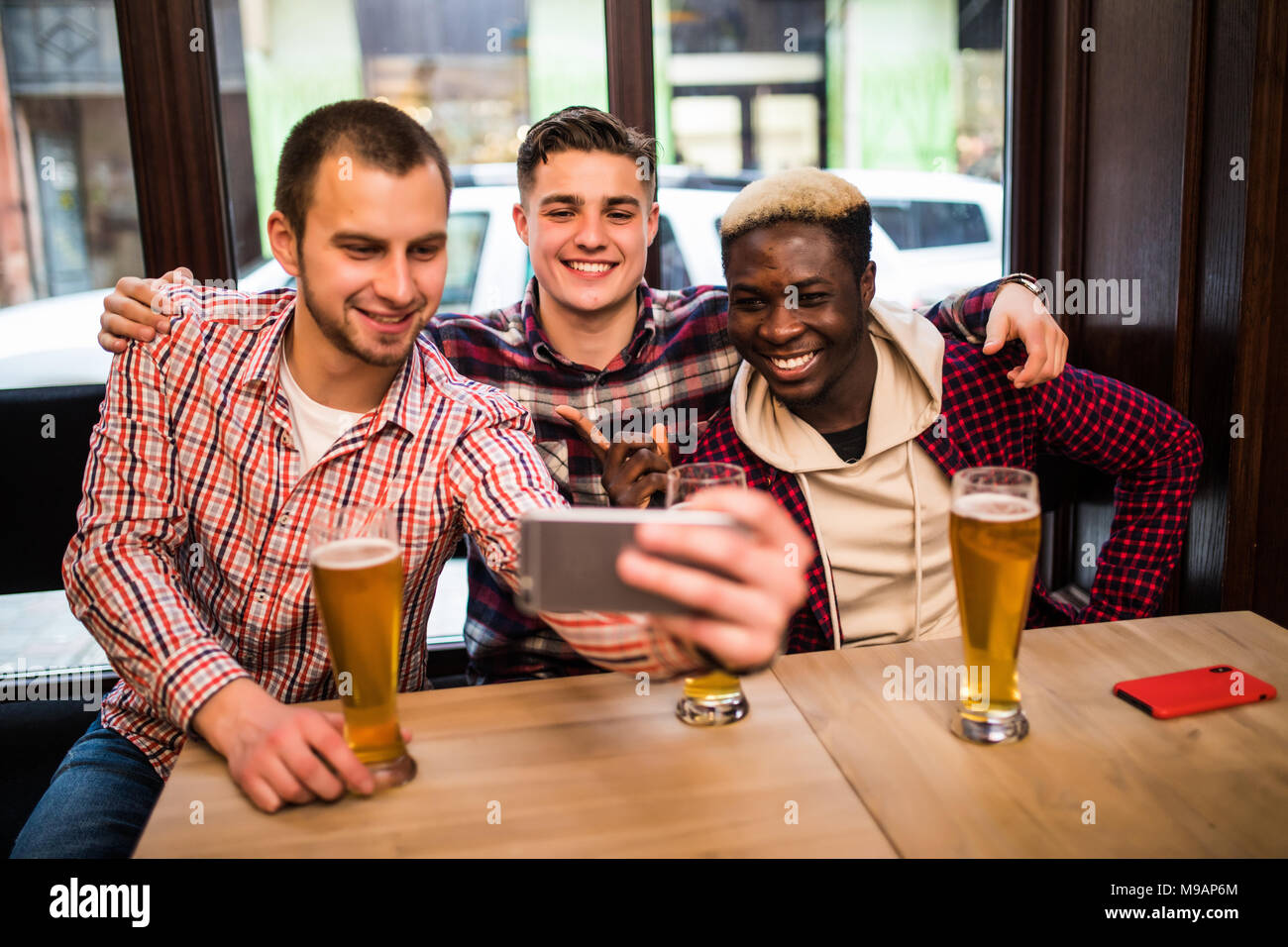 Allegro vecchi amici divertendosi prendendo selfie e bere birra nei pub. Foto Stock