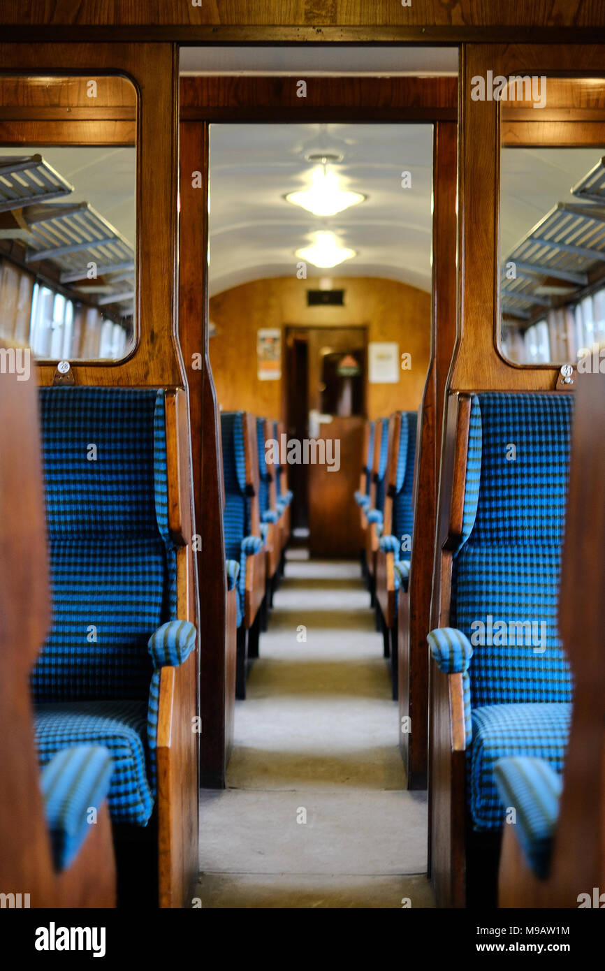 Interno di un carrello che porta i turisti alla Worth Valley Railway nel West Yorkshire che mostra la vecchia costruzione in legno e imbottita blu posti a sedere Foto Stock