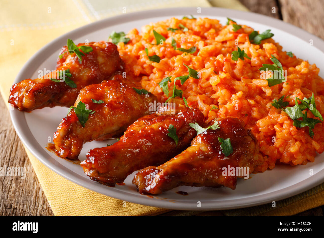 Cibo nigeriano party: Jollof riso con alette di pollo fritte close-up su una piastra orizzontale. Foto Stock