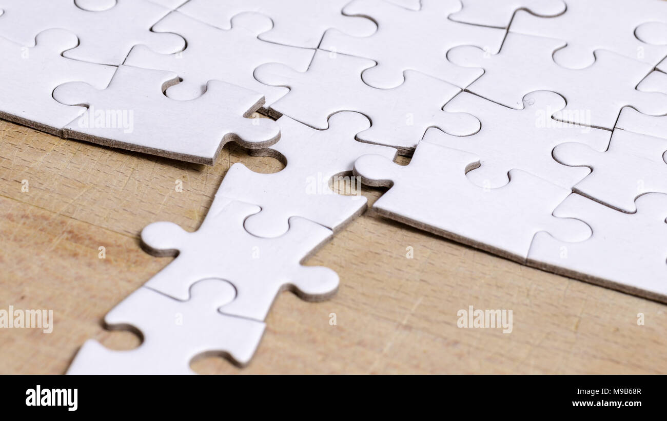 Bianco/jigsaw puzzle con una riga nella posizione sbagliata su un tavolo di legno sfondo, simbolo di problem solving e nuova visione Foto Stock