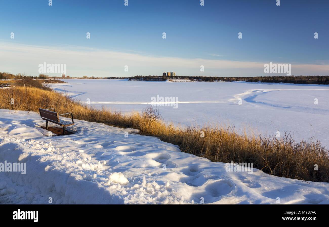 Parco isolato da banco e distante Snowy Glenmore serbatoio paesaggio panoramico a sud di Calgary Alberta a inizio primavera pomeriggio soleggiato Foto Stock