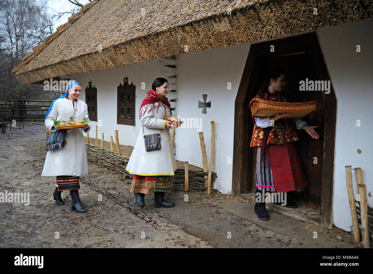 Le donne in ucraino abito nativo portando i pasti nella ricostruita casa rurale per celebrare la pasqua.Marzo 23, 2018. A Kiev, Ucraina Foto Stock