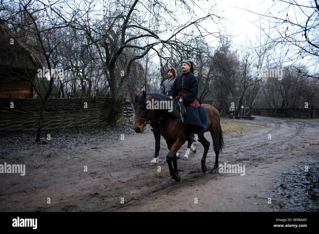 Gli uomini (cosacchi) in ucraino abito nativo Equitazione su cavalli lungo la strada rurale. La ricostruzione delle tradizioni popolari. Marzo 23, 2018. Kiev,Ucraina Foto Stock