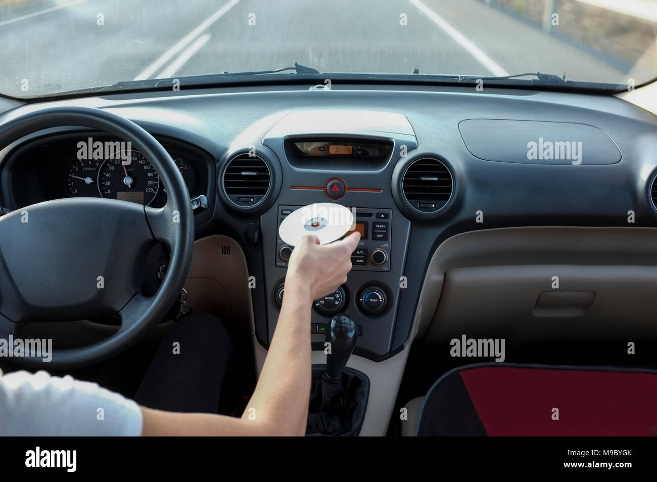 Donna inserendo il CD audio mentre ella è la guida. Cause di distrarsi incidenti alla guida del concetto. All'interno dell'auto visualizzare Foto Stock