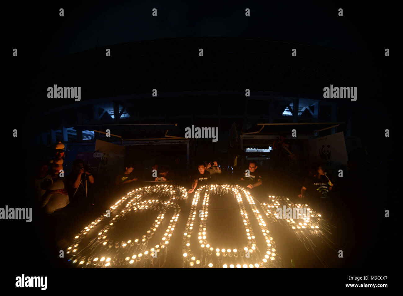 Jakarta. 24 Mar, 2018. Persone accendono le candele durante la celebrazione della messa a terra annuale campagna ora al Gelora Bung Karno stadium di Jakarta, Indonesia. Marzo 24, 2018. Credito: Agung Kuncahya B./Xinhua/Alamy Live News Foto Stock