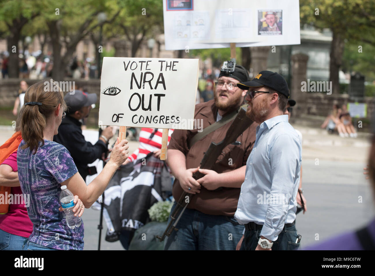 Donna con anti-NRA segno affronta pistola sostenitori dei diritti che trasportano armi lunghe in mezzo a quasi 10.000 dimostranti che protestavano della violenza pistola a marzo per le nostre vite a caso nel centro di Austin in Texas. Foto Stock