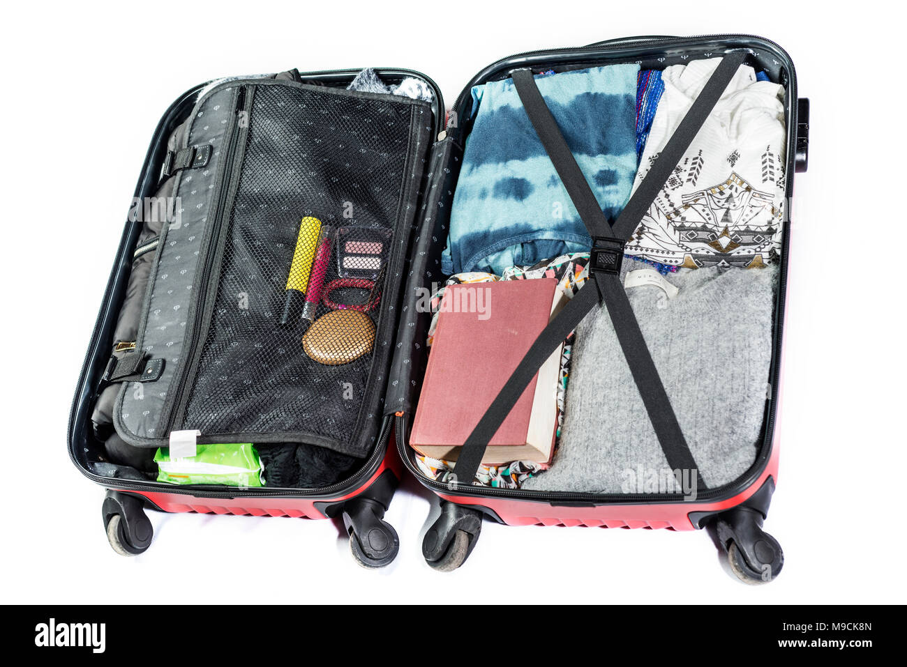 Valigia pronto a viaggiare con vestiti, libro e altri elementi, su sfondo bianco Foto Stock