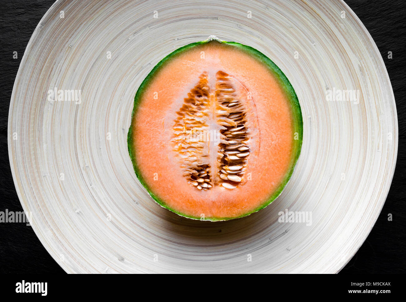 Tagliare ted nella metà del melone Hami frutti sulla piastra di bambù Foto Stock