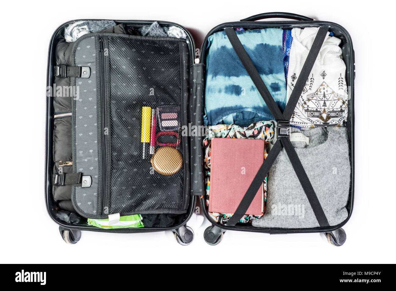 Valigia pronto a viaggiare con vestiti, libro e altri elementi, su sfondo bianco Foto Stock