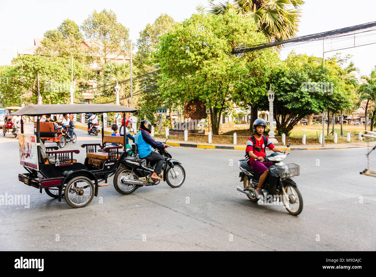 Un Tuk Tuk e scooter cross un nodo stradale, Siem Reap, Cambogia Foto Stock