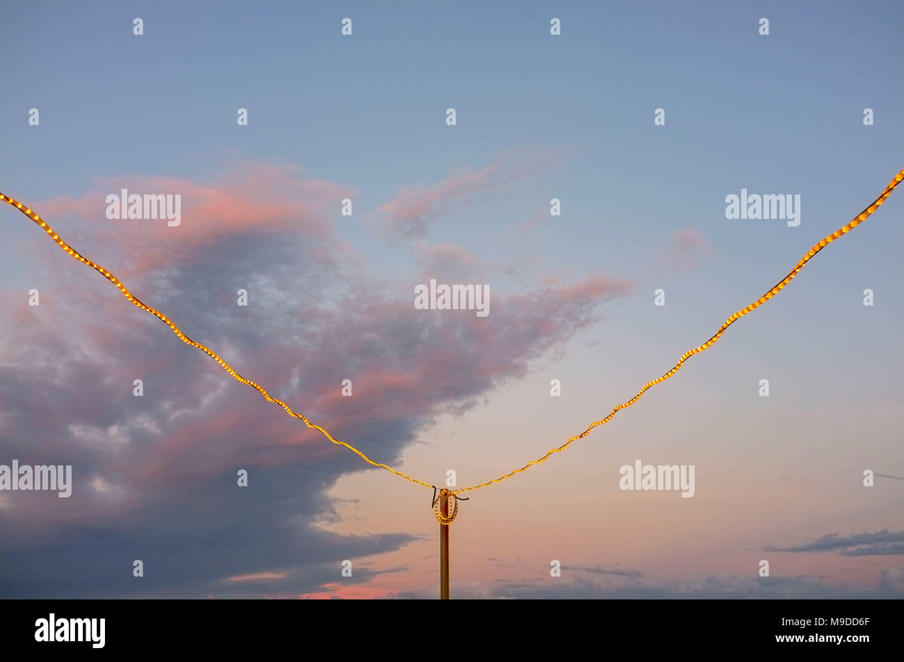 Luci da festa all'aperto, ghirlande leggere contro le nuvole della sera. Foto Stock