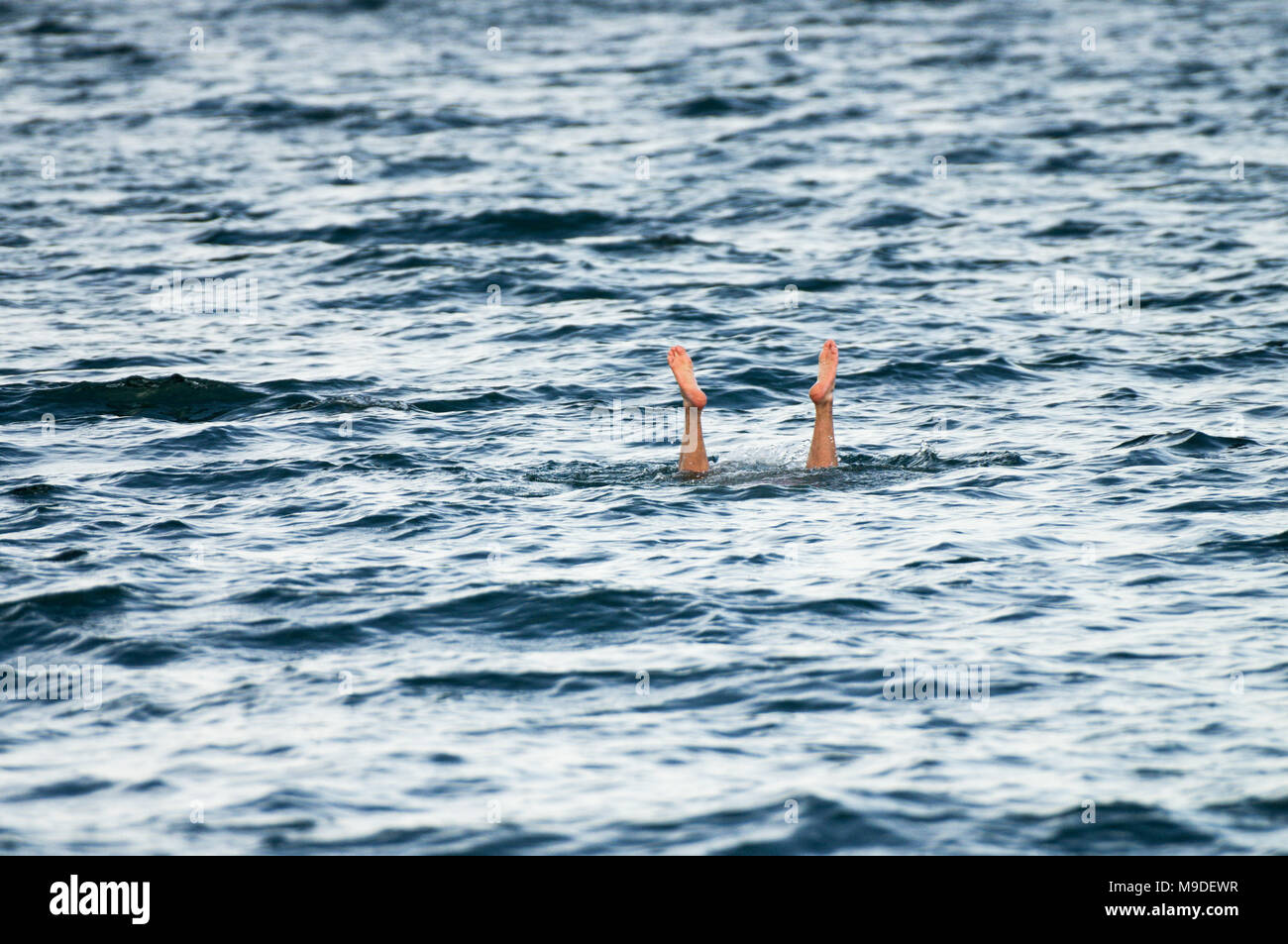Uomo di immersioni in laguna di Apoyo, con i suoi piedi spuntavano dell'acqua - western Nicaragua america centrale Foto Stock
