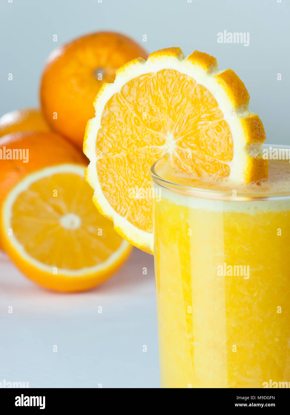 Un bicchiere di succo di arancia da vicino con una fetta di pane e frutta in background Foto Stock
