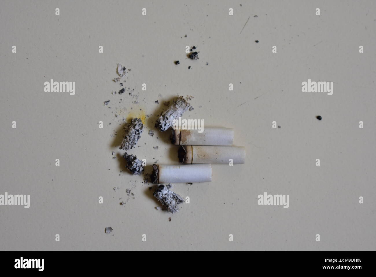 Un sacco di spezzone di sigaretta con la cenere dopo aver fumato in frantumi sul pavimento. Foto Stock