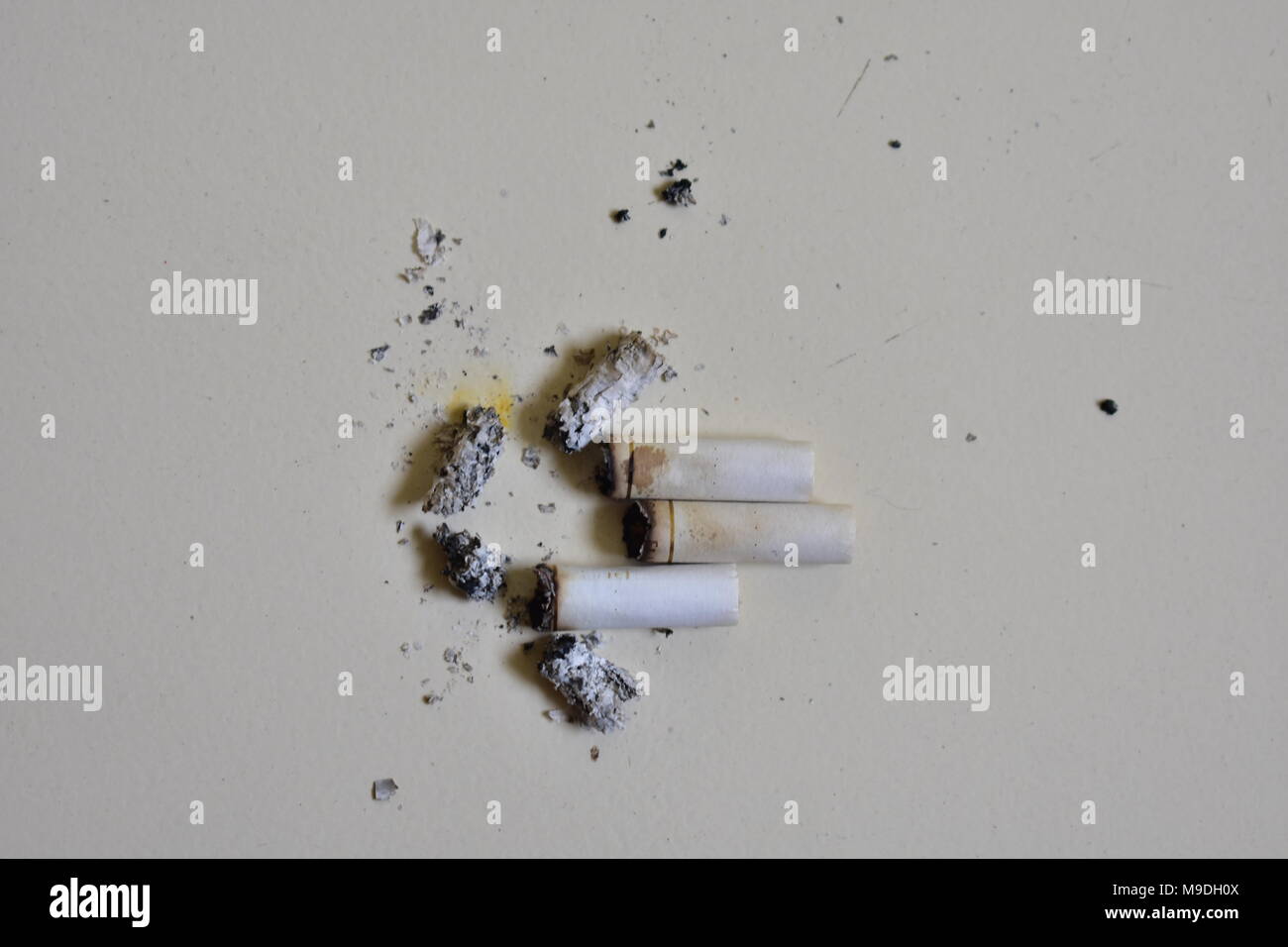 Un sacco di spezzone di sigaretta con la cenere dopo aver fumato in frantumi sul pavimento. Foto Stock