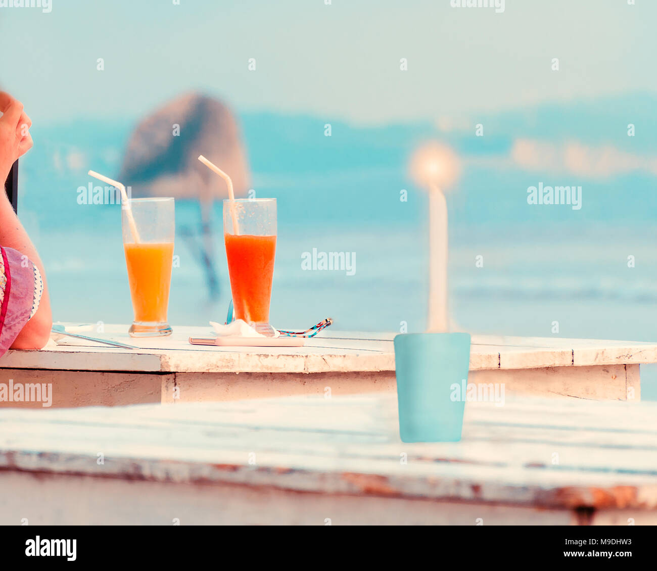 Donna mano , due bicchieri con succhi di frutta freschi, candela che brucia sul tavolo di legno nel bar sulla spiaggia. Concetto di vacanza, viaggio, romanticismo, vacanze Foto Stock