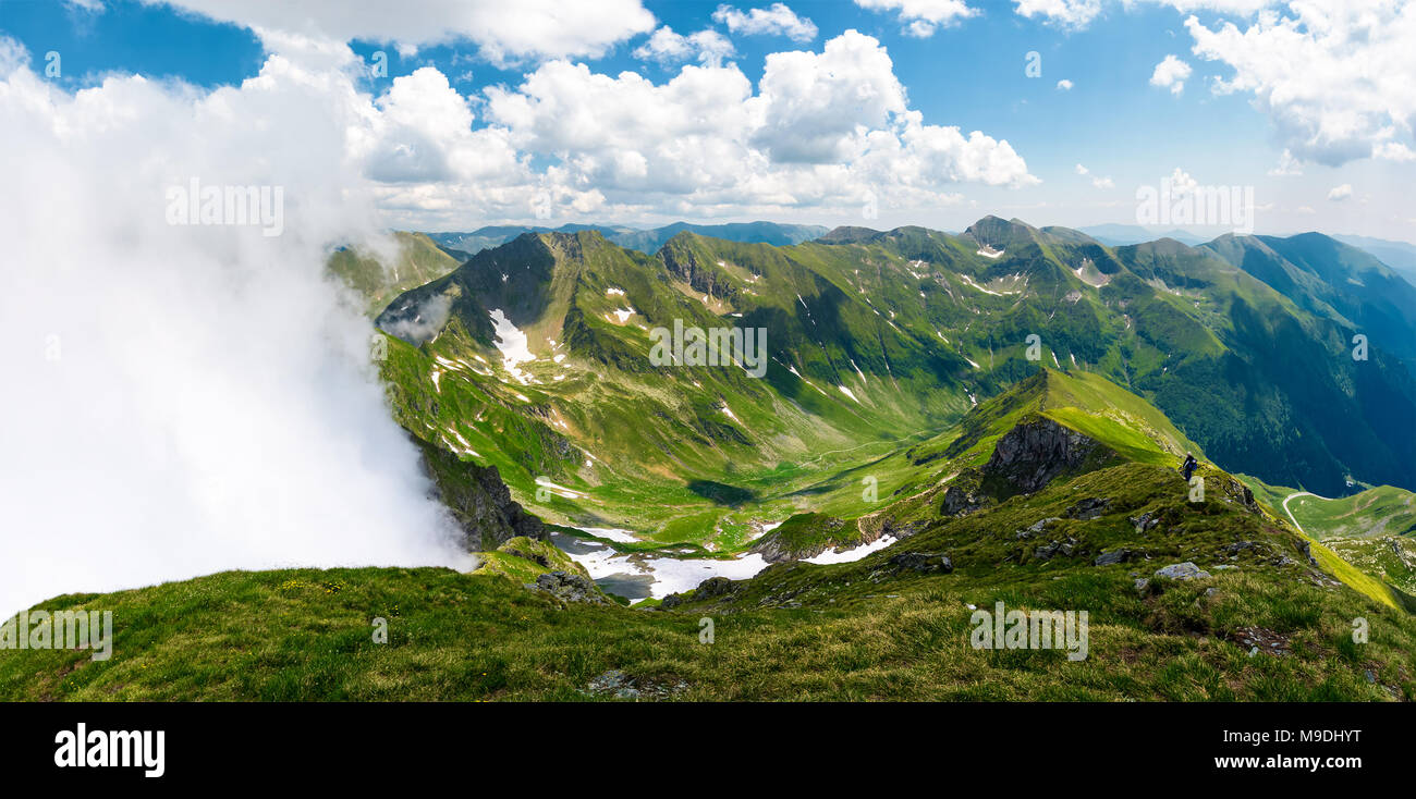 Panorama di montagna con nuvole in salita. bellissimo paesaggio con un po' di neve sui pendii erbosi. destinazione popolare per le escursioni in montagna Fagaras o Foto Stock