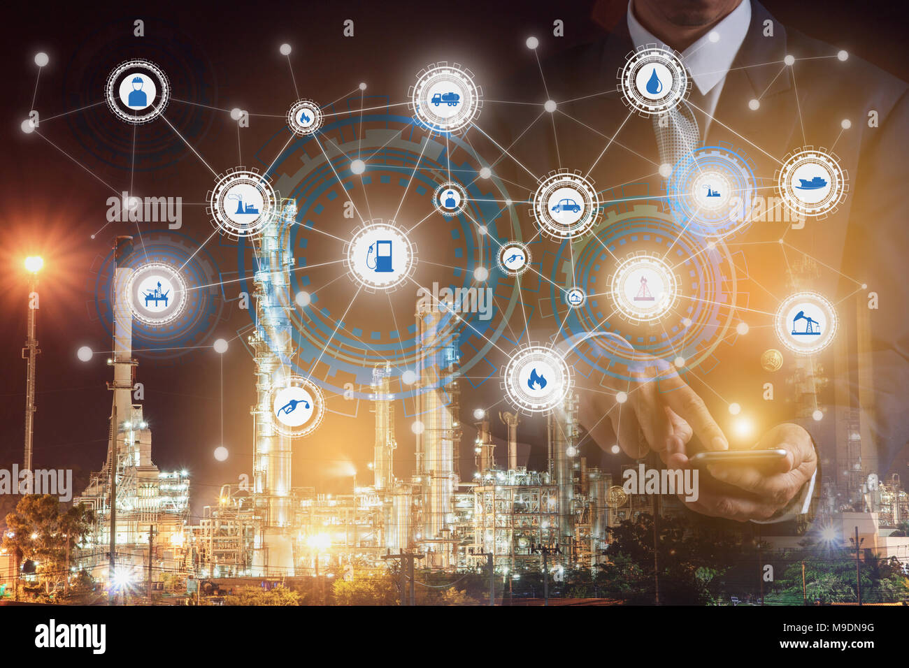 La doppia esposizione di imprenditore tenere in mano di lavoro dello smartphone con la raffineria di petrolio pianta del settore industria e le icone. In fabbrica la notte come la comunicazione Foto Stock