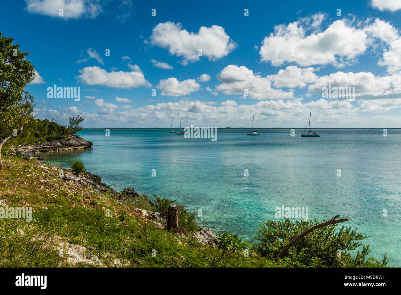 Isola delle Bahamas vista oceano turchese che mostra le barche a vela in acqua in una luminosa giornata di sole con un cielo azzurro e alto contrasto nuvole Foto Stock