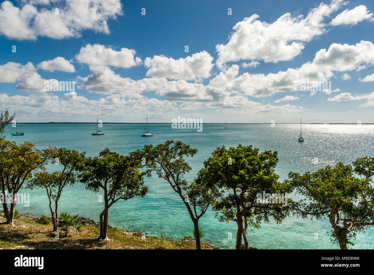 Isola delle Bahamas vista oceano turchese che mostra le barche a vela in acqua in una luminosa giornata di sole con un cielo azzurro e alto contrasto nuvole Foto Stock