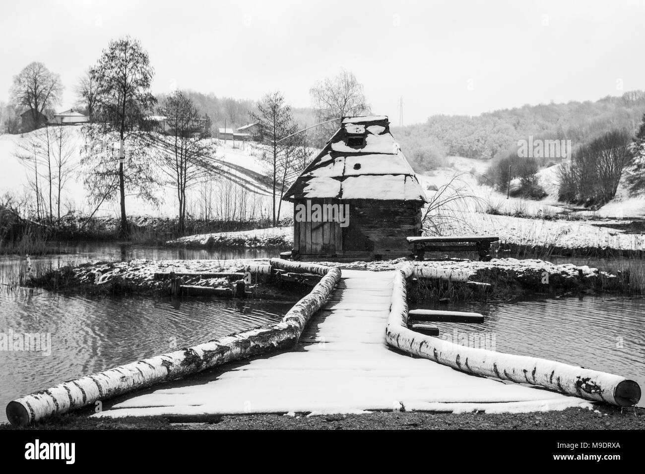 Legno mulino sulle sponde di un lago in inverno durante il giorno nevoso Foto Stock