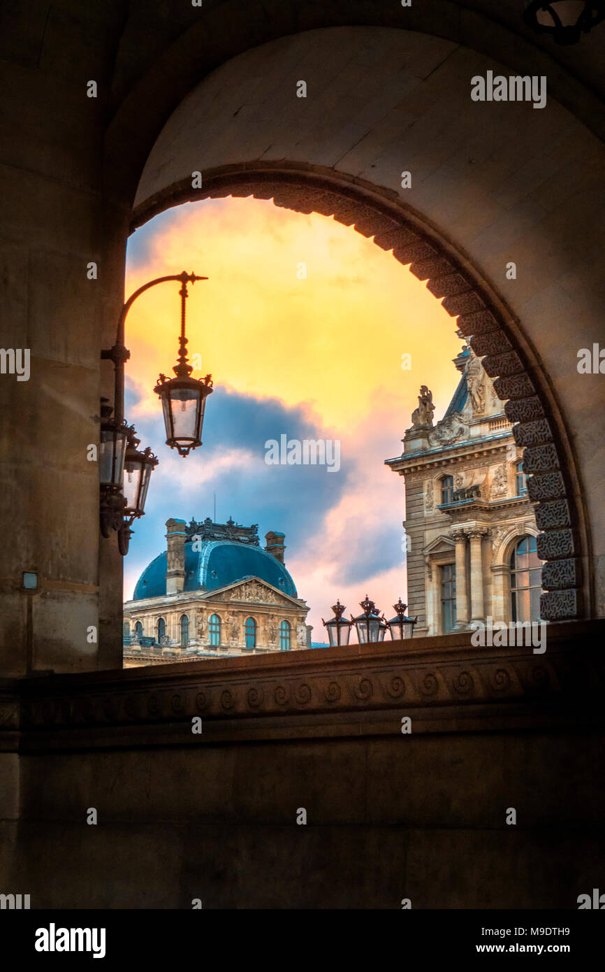 Louvre visto attraverso arch con lampade e colorata del cielo della sera Foto Stock